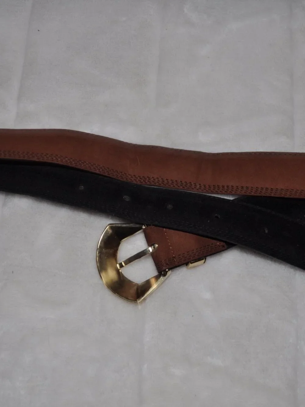 Women's belt features distinctive gold-tone metal hardware, including a unique